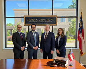 Experienced DUI defense lawyers standing in law office with courthouse view and legal books.